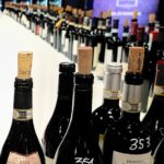 Assaggio comparativo di Barolo 2022: bottiglie numerate esposte su tavolo durante degustazione con schermo di proiezione sullo sfondo