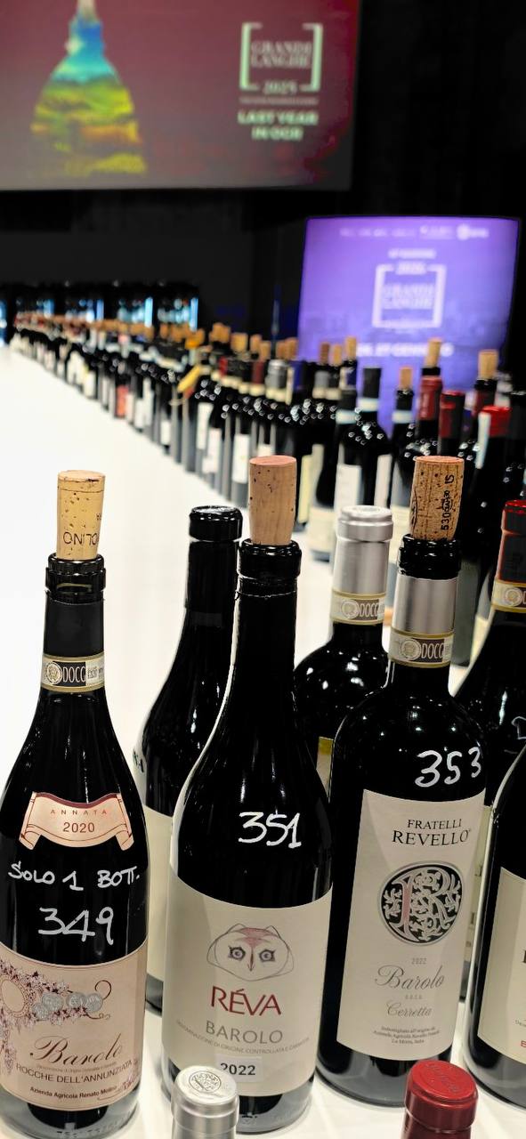Assaggio comparativo di Barolo 2022: bottiglie numerate esposte su tavolo durante degustazione con schermo di proiezione sullo sfondo