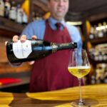 Sommelier versa vino bianco Antinori in calice durante degustazione in enoteca