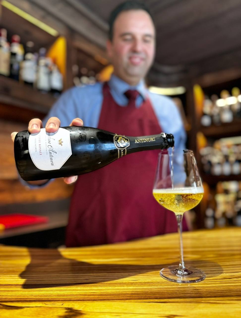 Sommelier versa vino bianco Antinori in calice durante degustazione in enoteca